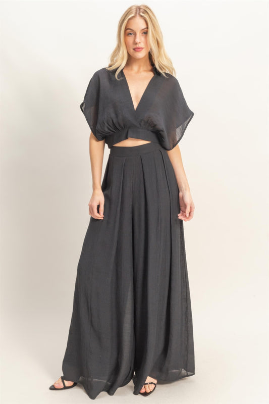 A woman posing in a black collar wrap top & wide-leg pants set.