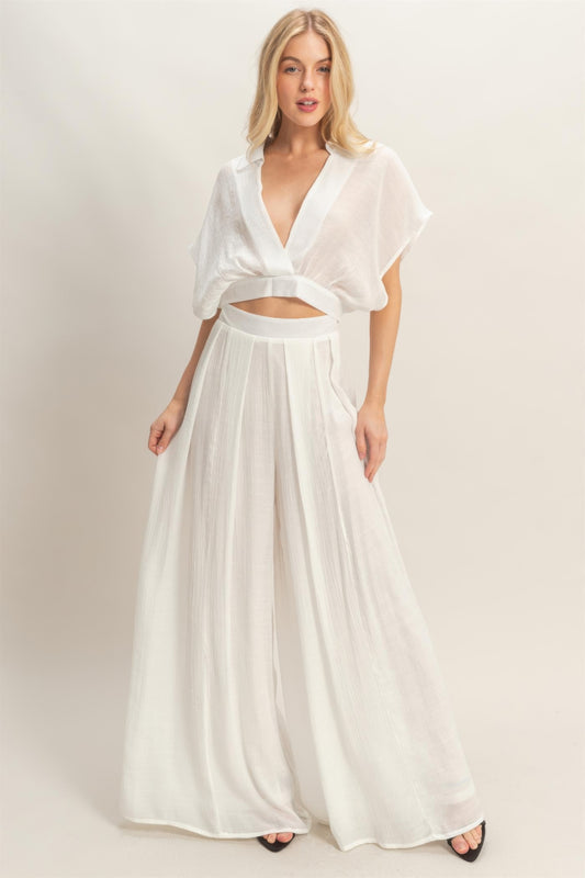 A woman posing in a white collar wrap top & wide-leg pants set.