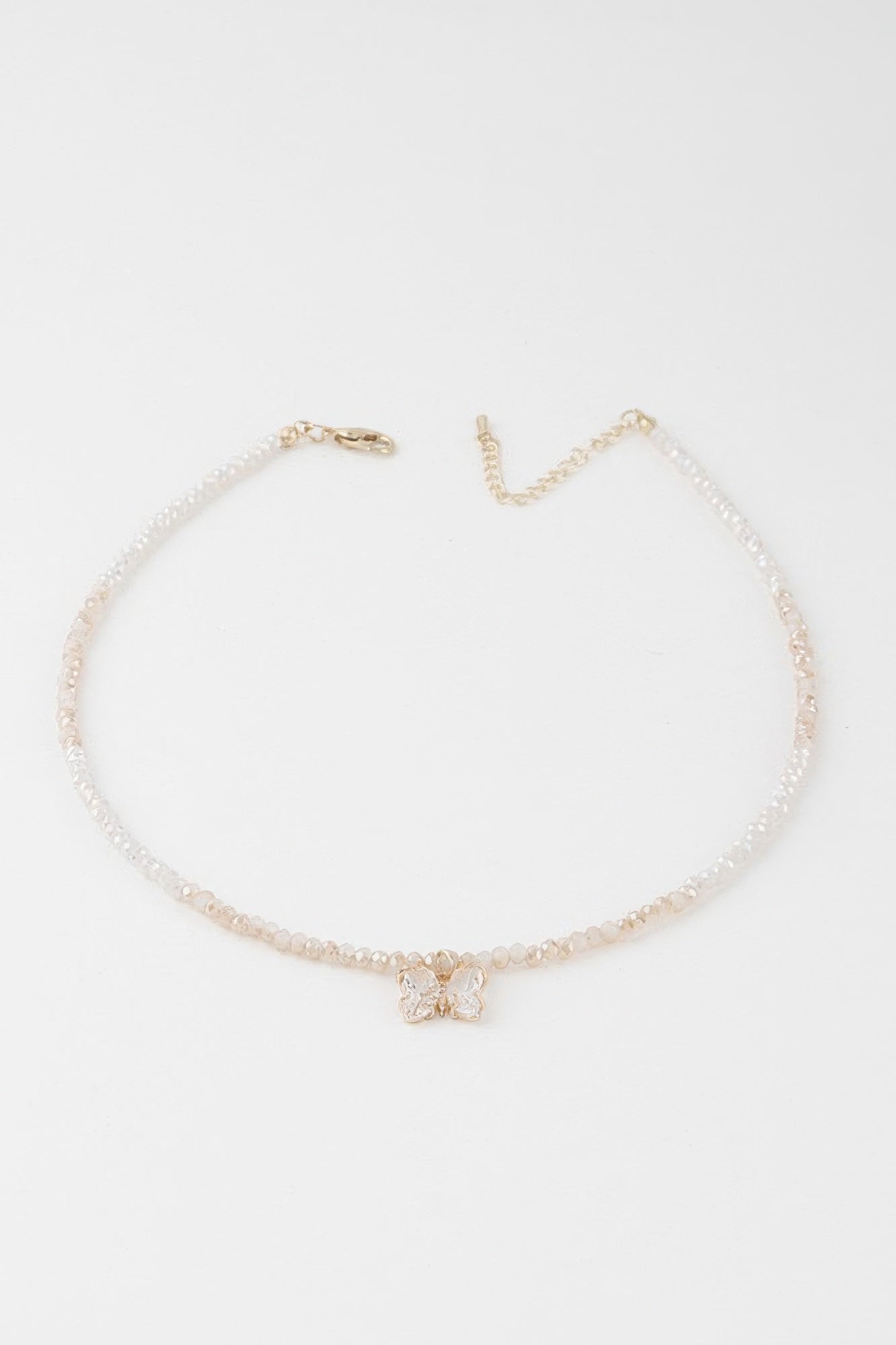 A gold white colored crystal butterfly beaded necklace.