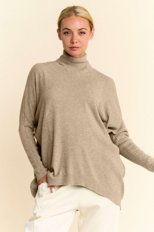 A woman posing in a khaki turtleneck long sleeve knit top.