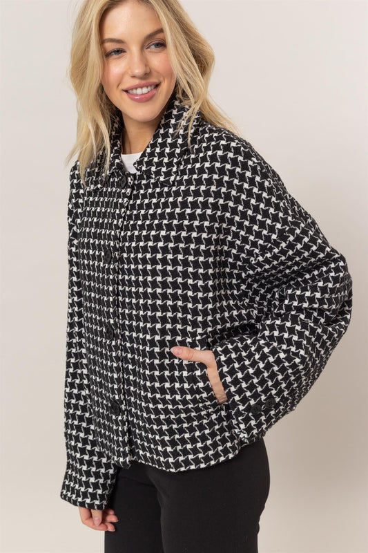 A woman posing in a black tweed plaid collar jacket.