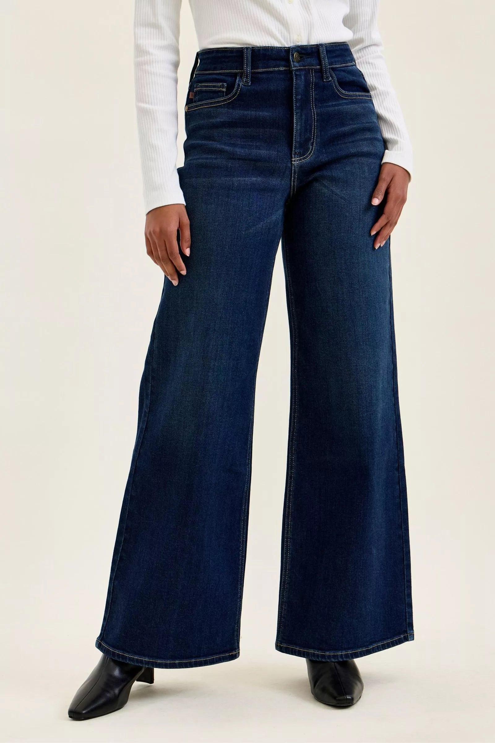 A woman posing in dark wash high-waisted wide-leg jeans.