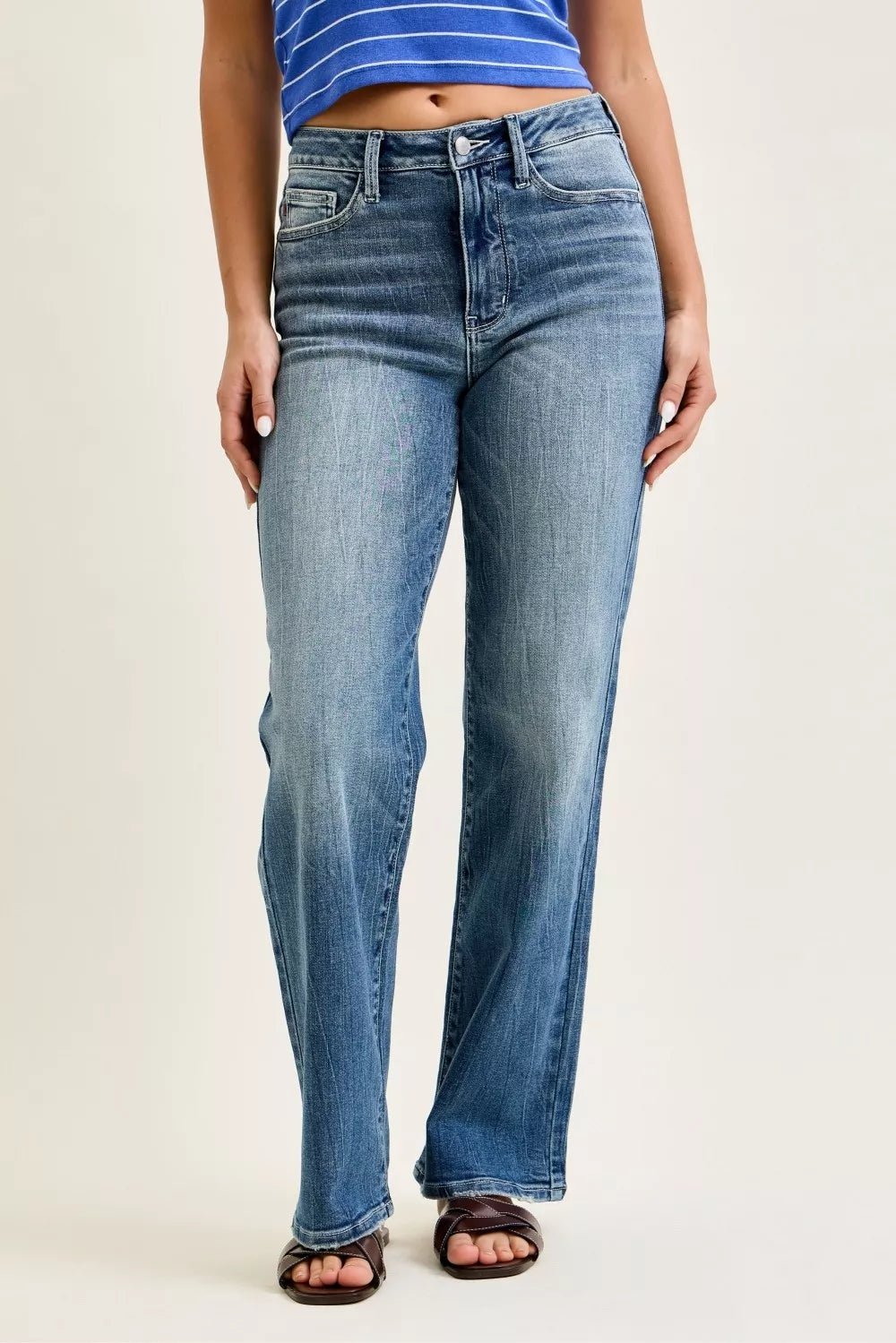A woman posing in medium-wash mid-rise 90s straight jeans.