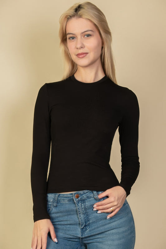 A woman posing in a black ribbed long sleeve top.