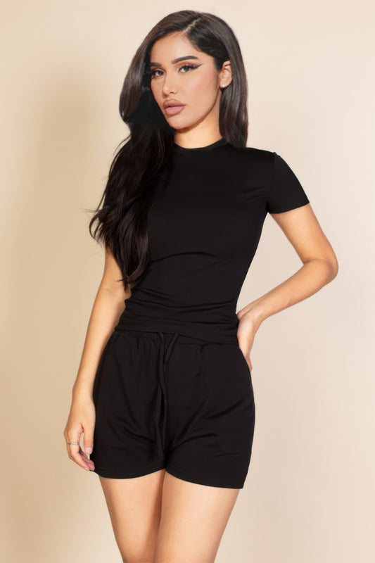 A woman posing in a black ribbed short sleeve top.