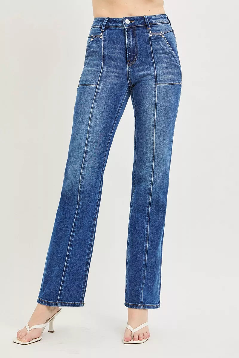 A woman posing in dark wash high-rise straight patch pocket seamed jeans.