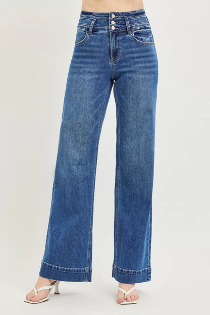 A woman posing in dark wash high-rise wide waistband jeans.