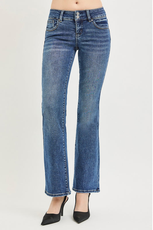 A woman posing in medium wash tummy control low-rise bootcut jeans.