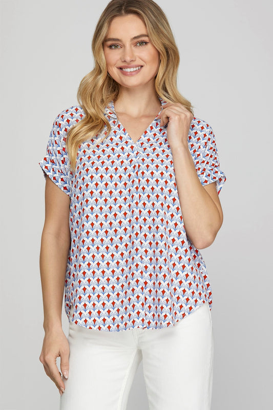 A woman posing in a red printed johnny collar blouse.