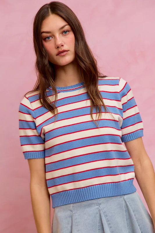 A woman posing in a red, white, and blue striped knit short sleeve sweater top.