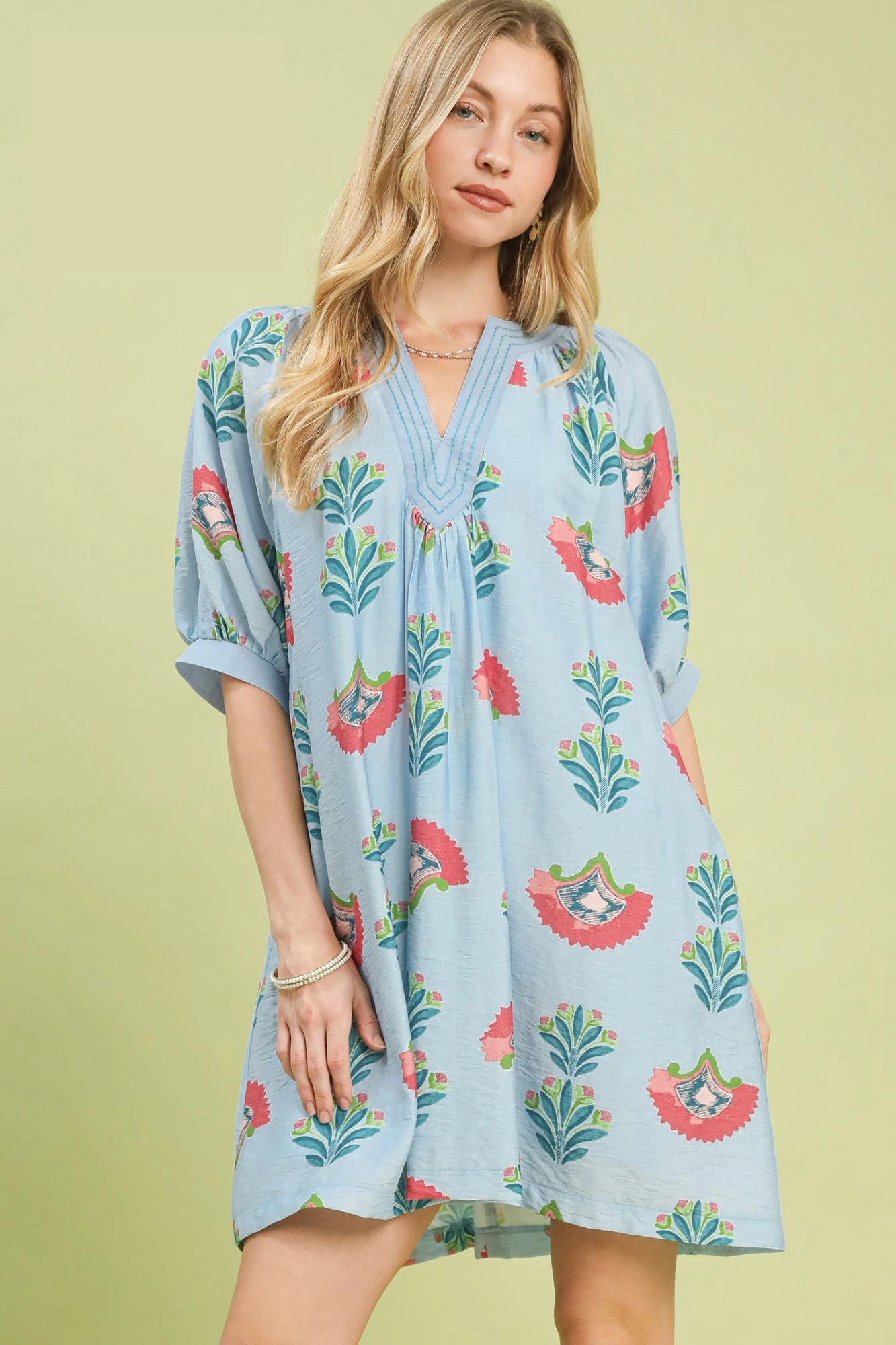 A woman posing in a light blue abstract print mini dress.