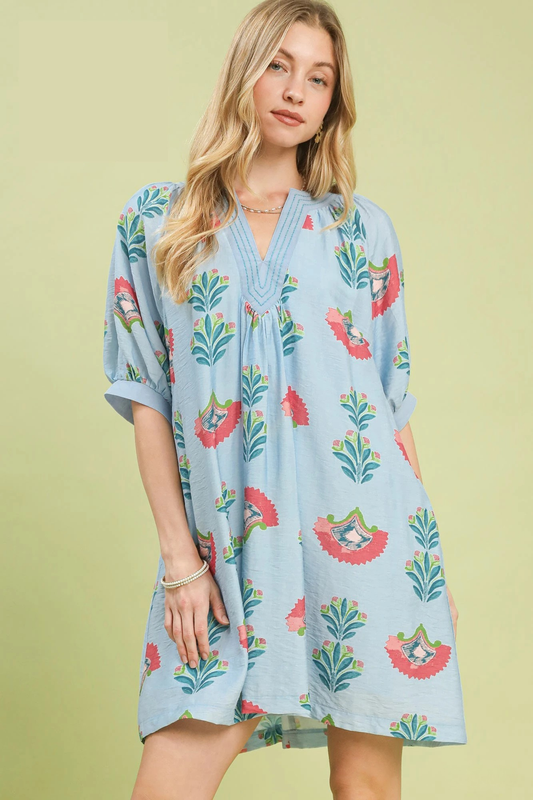 A woman posing in a light blue abstract print mini dress.