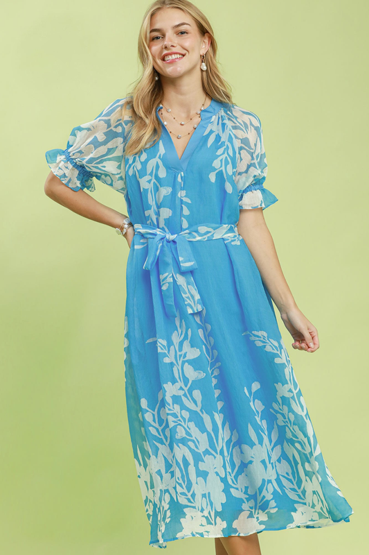 A woman posing in a blue floral print waist tie pocket midi dress.