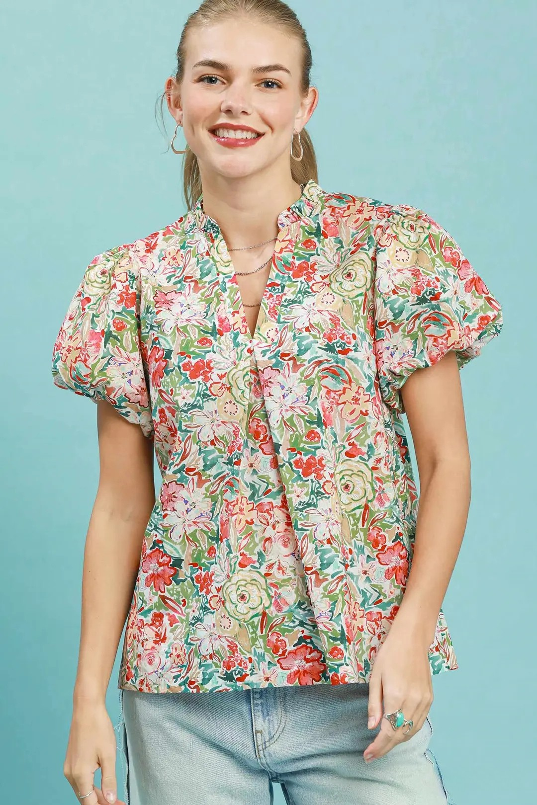 A woman posing in a colorful coral mix floral puff sleeve blouse.