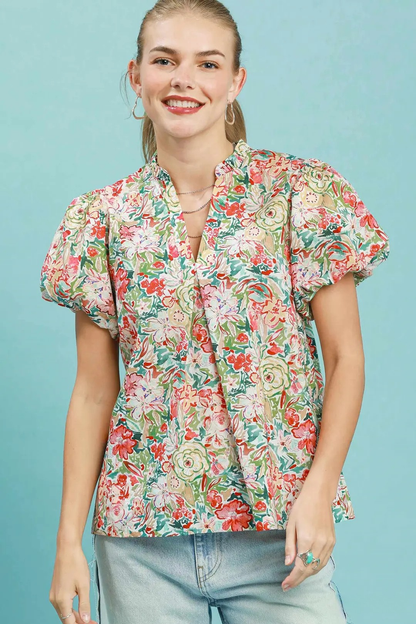 A woman posing in a colorful coral mix floral puff sleeve blouse.