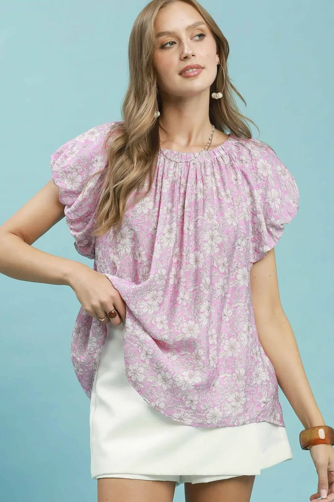 A woman posing in a pink floral puff sleeve blouse.
