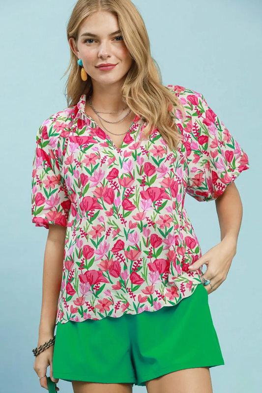 A woman posing in a red and pink floral mix puff sleeve blouse with a scalloped hem.