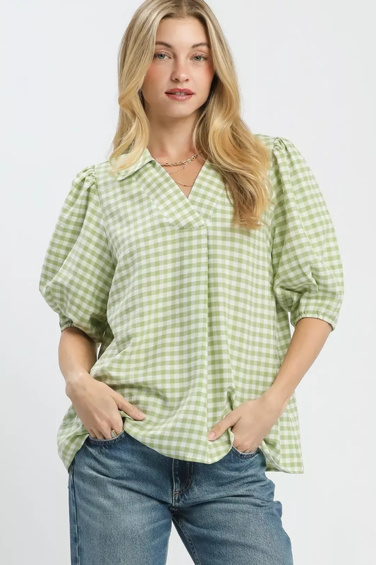 A woman posing in a sage colored gingham puff sleeve collar blouse.