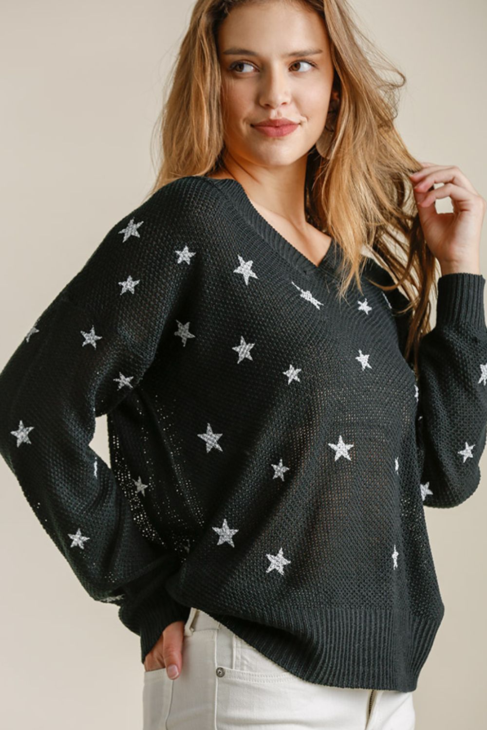 A woman wearing a star pattern black v-neck sweater.