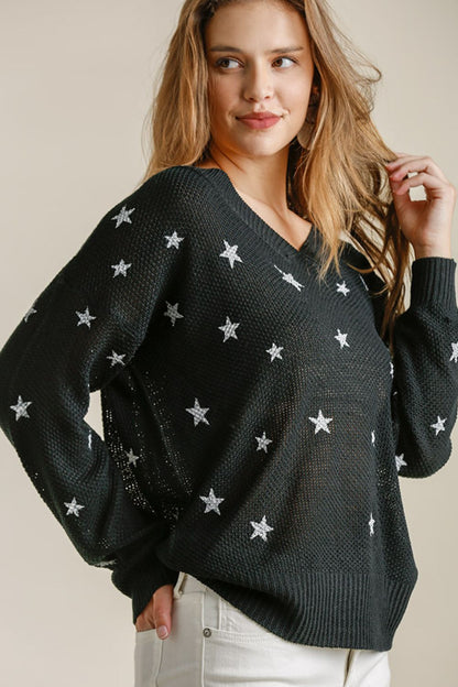 A woman wearing a star pattern black v-neck sweater.