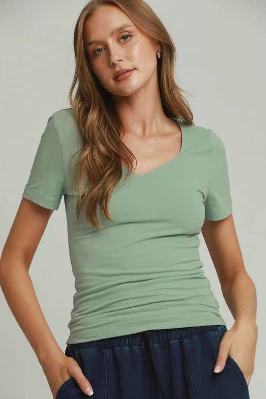 A woman posing in a dusty mint colored sweetheart neckline double-lined top.