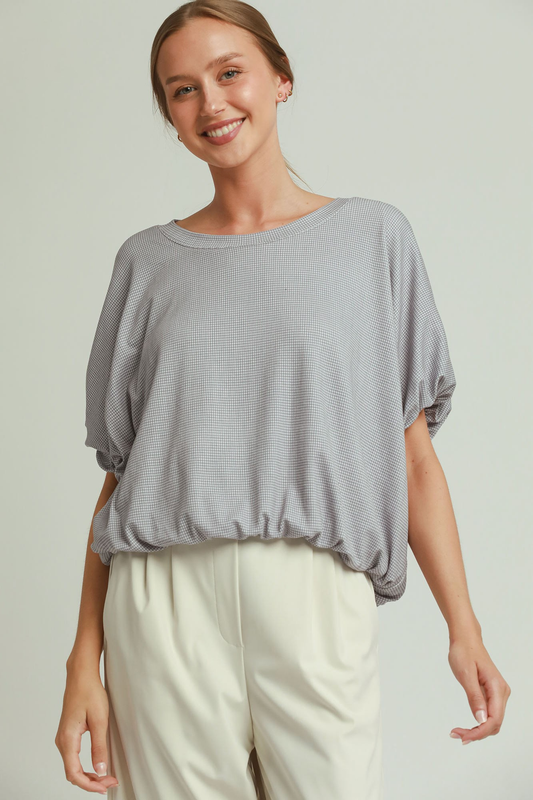 A woman posing in a gray and white checkered bubble hem textured top.