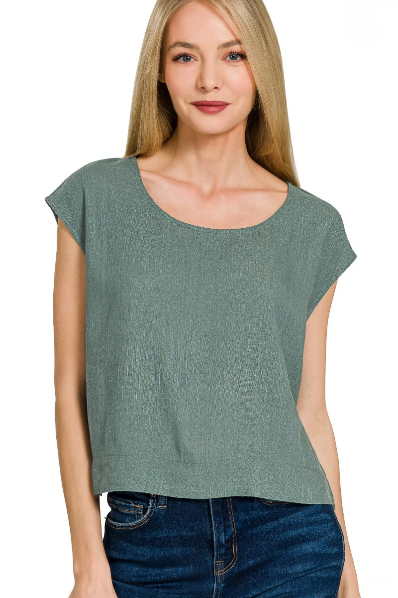 A woman posing in an ash jade linen sleeveless top.