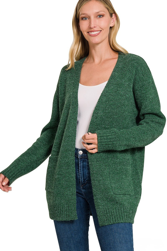 A woman posing in a dark green open cardigan.