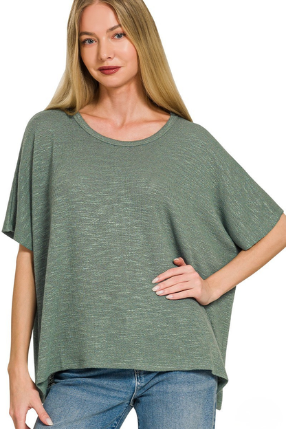 A woman posing in an ash jade colored slub oversized hacci top.
