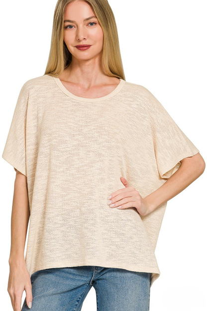 A woman posing in a taupe sand colored slub oversized hacci top.