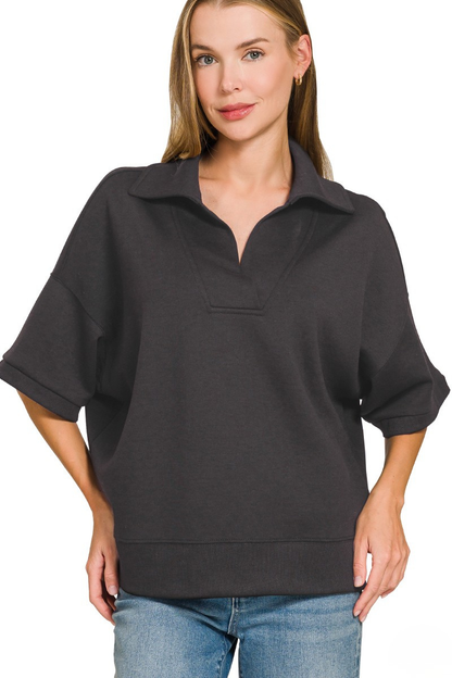 A woman posing in a black scuba fabric collar pullover top.