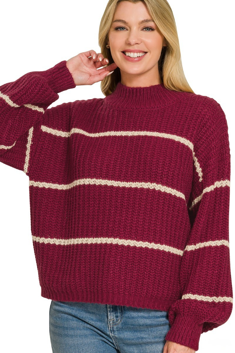 A woman posing in a cabernet red striped oversized sweater.