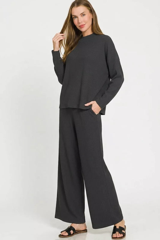 A woman posing in a black viscose sweater top and pants set.