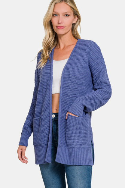 A woman posing in a marlin blue waffle knit open cardigan.