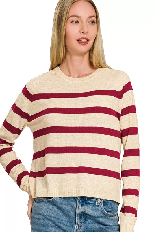 A woman wearing a beige wool blend sweater with dark burgundy stripes.