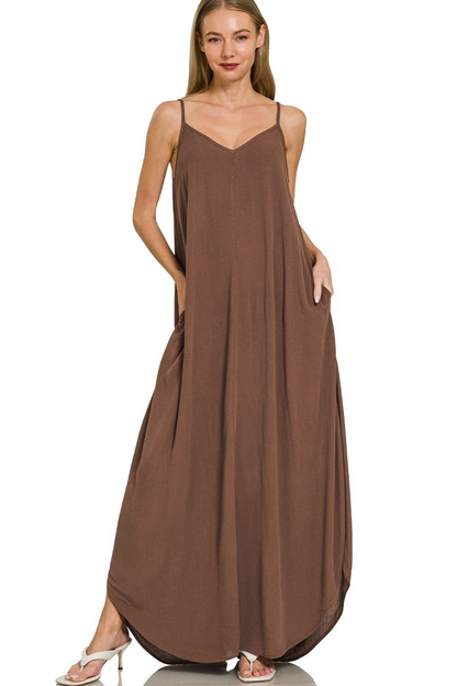 A woman posing in a brown woven crinkle cami pocket maxi dress.